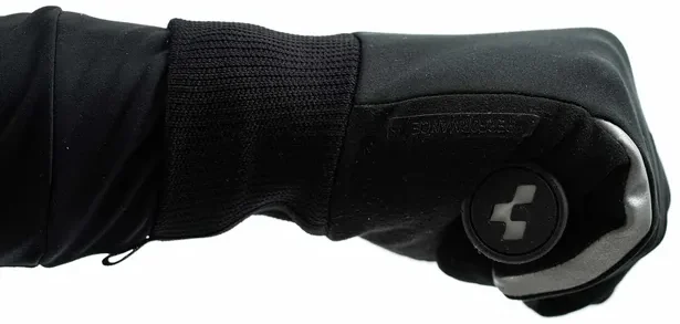 Nahaufnahme des Arms einer Person in einem schwarzen CUBE Handschuhe Performance All Season Langfingerhandschuh und schwarzem Ärmel, mit geballter Faust. Der Handschuh hat einen strukturierten Bereich und ein kreisförmiges Logo in der Nähe der Knöchel auf weißem Hintergrund., Ansicht 3