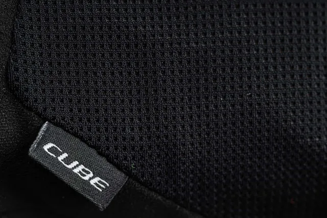Nahaufnahme der CUBE Handschuhe kurzfinger X NF aus schwarzem, strukturiertem Stoff mit gitterartigem Netzmuster und einem aufgenähten Etikett mit der Aufschrift "CUBE" in Weiß - zu finden auf Radsportartikeln bei Mr. Bike Lichtenfels., Ansicht 3