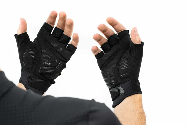Eine Person hebt ihre Hände vor einem weißen Hintergrund und trägt schwarze CUBE Handschuhe kurzfinger X NF fingerlose Handschuhe mit gepolsterten Handflächen und sichtbarem "Comfort Foam"-Text., Ansicht 6