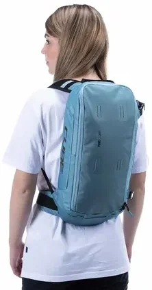 Person mit weißem T-Shirt, die von sich wegschaut und einen hellblauen CUBE Rucksack PURE 12 CMPT mit schwarzen Trägern vor einem schlichten weißen Hintergrund trägt., Ansicht 4
