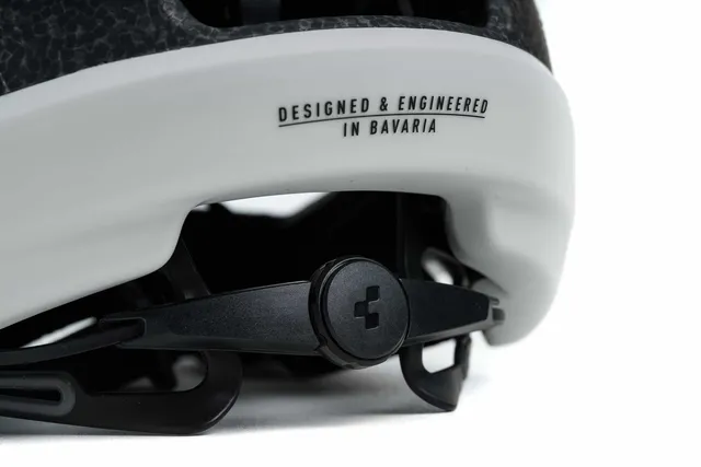 Nahaufnahme des hinteren Verstellmechanismus eines weiß-schwarzen CUBE Helm HERON Fahrradhelms mit dem Schriftzug Mr. Bike Lichtenfels und dem Aufdruck DESIGNED & ENGINEERED IN BAVARIA., Ansicht 2