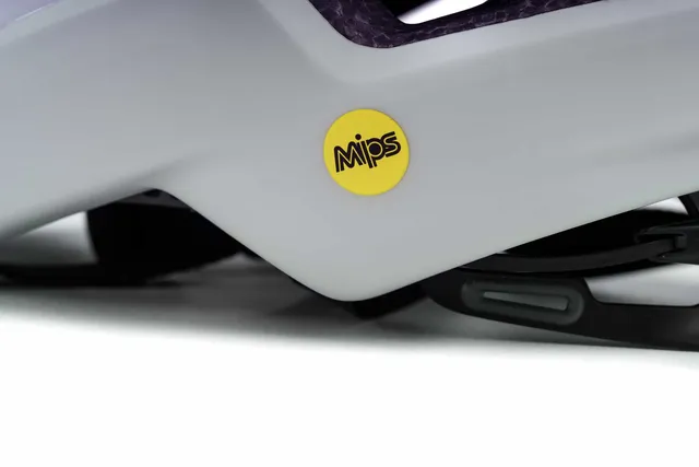 Nahaufnahme des CUBE Helm HERON bei Mr. Bike Lichtenfels, mit gelbem, kreisförmigem MIPS-Logo an der Seite und sichtbaren Helmriemen darunter., Ansicht 3