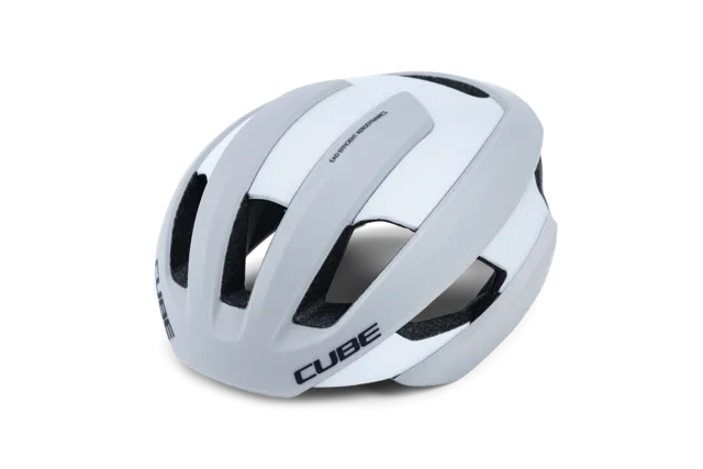 Der CUBE Helm HERON ist ein weiß-grauer Fahrradhelm mit schwarzer Innenpolsterung und dem Schriftzug "CUBE" auf der Front und an der Seite. Erhältlich bei Mr. Bike Lichtenfels, abgebildet vor einem schlichten weißen Hintergrund., Ansicht 5