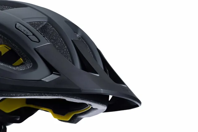 Nahaufnahme der Vorderseite eines schwarzen Fahrradhelms mit Visier von CUBE Helm FLEET. Hervorzuheben sind die detaillierten Belüftungsöffnungen und die gelbe Innenpolsterung vor einem weißen Hintergrund., Ansicht 2