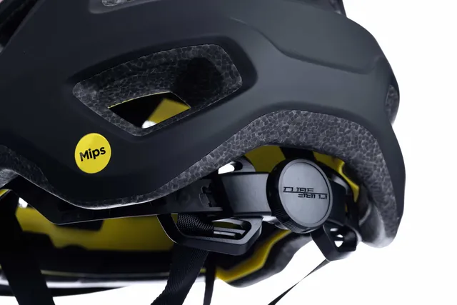 Nahaufnahme eines schwarzen CUBE Helm FLEET-Helms mit gelbem Mips-Aufkleber, verstellbarem Riemen, hinterem Einstellsystem und sichtbarer Schaumstoffpolsterung mit Belüftungslöchern für mehr Komfort., Ansicht 4