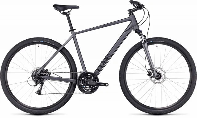 Ein CUBE Nature graphite'n'black Hybridbike mit mattschwarzem Finish, geradem Lenker, schlankem Rahmen, Federgabel, Scheibenbremsen und großen Reifen wird von der Seite vor einem weißen Hintergrund gezeigt.