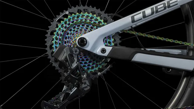 Das CUBE Stereo ONE77 C:68X SLT 29 in flashwhite'n'grey von Mr. Bike Lichtenfels ist mit schwarzen, goldenen und blauen Komponenten, dicken Maxxis-Reifen, Scheibenbremsen und einer Dropper-Sattelstütze ausgestattet - alles auf einem schlichten weißen Hintergrund., Ansicht 10