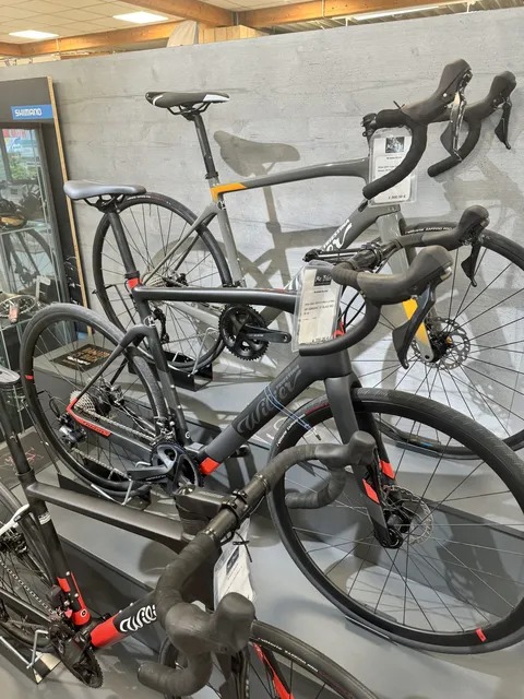 Ein Wilier Bike Cento1 Hybrid Ultegra HY-NDR30AC Y1 in Schwarz mit roten Akzenten (Größe XL) steht auf einem Ständer bei Mr. Bike Lichtenfels, komplett mit Preisschild. Links daneben steht eine Glasvitrine., Ansicht 2