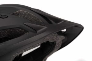 Nahaufnahme eines mattschwarzen CUBE Helm STEEP Fahrradhelms, der die strukturierte Außenschale, die Belüftungsöffnungen und das Schutzvisier hervorhebt. Der Helm hat kantige Designlinien und eine sichtbare Innenpolsterung.